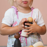 Ein Kleinkind hält zwei Grapat Adult Nins Holzfiguren eng an sich.