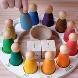 Der "Perpetual Calendar" Jahreskreis von Grapat mit den 4 Jahreszeiten Plattformen und den 12 Jahreszeiten Freunden in den verschiedenen Farben. In der Mitte die Zahlenwürfel und ein Holzbecher, in den gerade die Holzfigur für Februar gestellt wird.