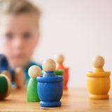 Das blaue Grapat "Mates" Toepfchen aus Holz, darin ein blauer Nin, im Hintergrund sind noch weitere Grapat Spielmaterialien in verschiedenen Farben.
