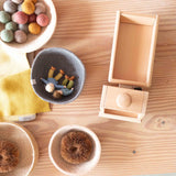 Blick auf einen Fagus LKW-Kipper aus Holz mit leerer Ladefläche, daneben Körbe und Holzschüsseön mit Püppchen aus Filz, Filzkugeln und anderem freien Spielmaterial.