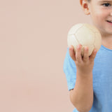 Ein lächelndes Kind hält den kleinen Lederball von Lautenbach, der einen Durchmesser von 9 cm hat, in der Hand.