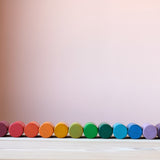 Die bunten Zylinder aus Holz vom Grapat Spielmaterial Lola liegend aufgereiht, farblich sortiert als Regenbogen.