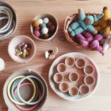 Angebot im Pikler Spielraum: in verschiedenen Körben und Holzschalen liegen Speilfiguren, kleine Stoffpuppen, Filzbälle, Motorikringe, Filzringe und vieles mehr.