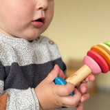 Ein Baby hält den Bio-Greifling Rasselbäumchen von Nic in der Hand und staunt.