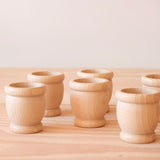 Die sechs Holzbecher Grapat "Mates" aufgestellt auf einer Holzplatte.