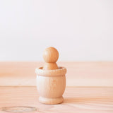 Ein kleiner Holzbecher Grapat Mates, darin eine Spielfigur aus Holz, ein Grapat Nin.